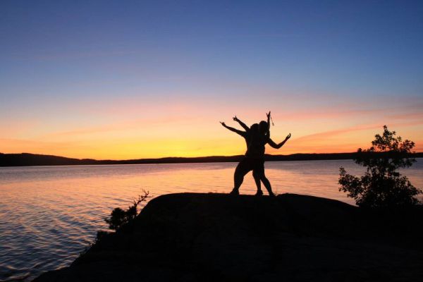Två svarta siluetter på ett berg i solnedgång.