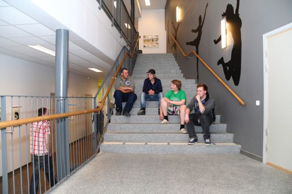 Fyra elever sitter i trappan inne i skolhuset