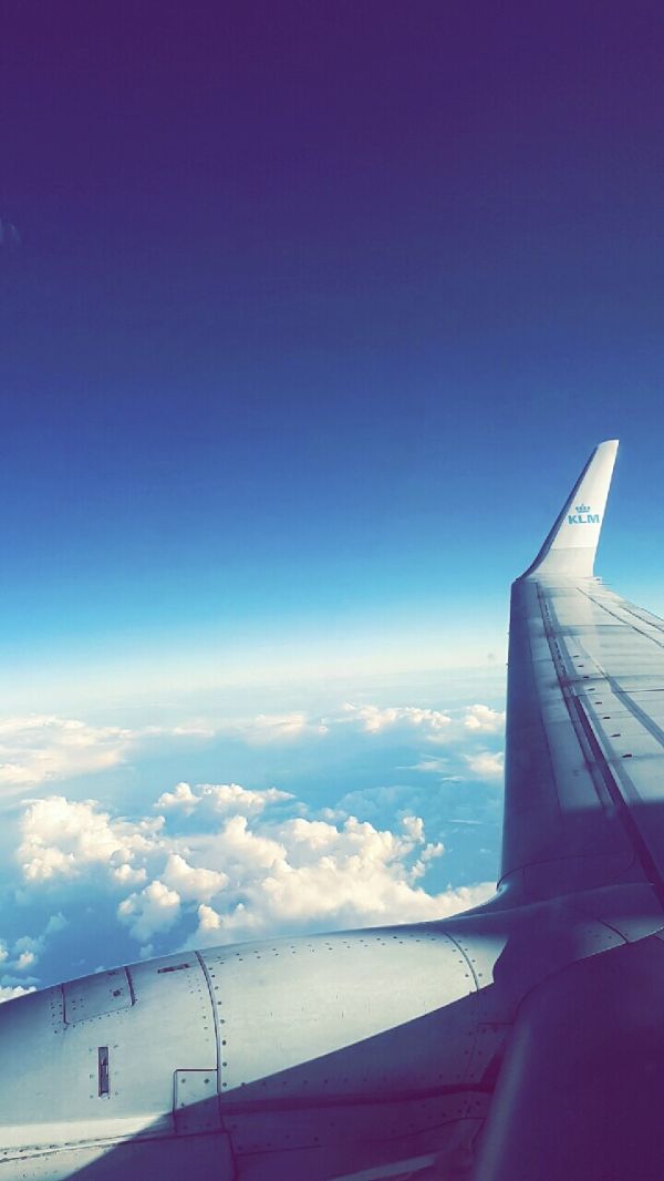 Foto taget från ett flygplan på flygplansvinge i luften med utsikt över blå himmel och moln.
