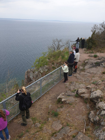Flera människor på ett berg, tittar på utsikten över sjön