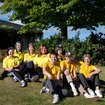 Åtta ungdomar sitter tillsammans på gräsmattan