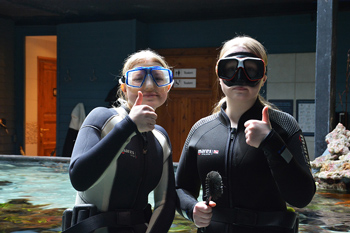 Tv&aring; tjejer i v&aring;tdr&auml;kt g&ouml;&auml;r tummen upp