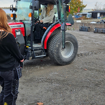 En tjej sitter i en liten traktor och backar