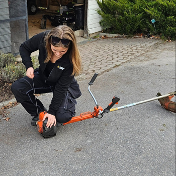 En tjej reparerar en röjmotorsåg