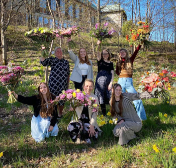 Sju kvinnor håller varsin blombukett