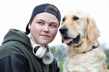 En kille och en beigefärgad stor hund