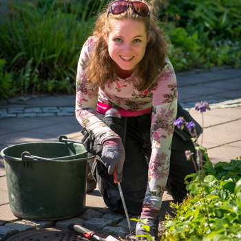 Glad tjej gr&auml;ver i en rabatt