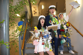 Tre glada studenter med blommor runt halsen