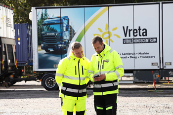 Två varselklädda män framför en lastbil