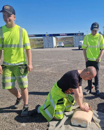 Tre personer i varselkläder, övar HLR